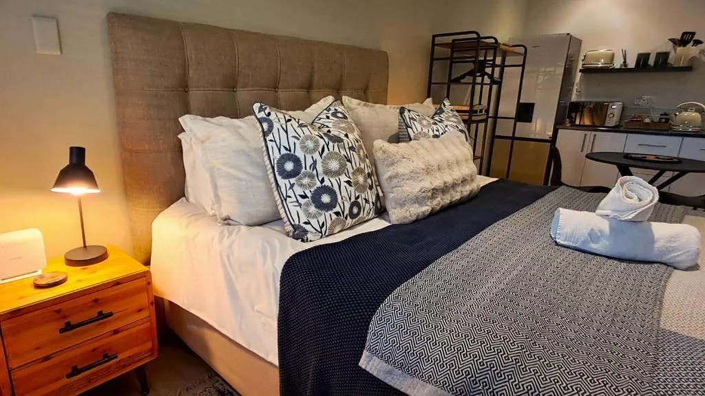 Bedroom with upholstered headboard, decorative pillows, and warm bedside lighting