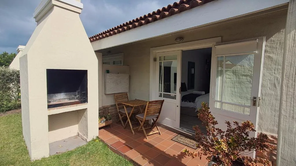 Covered patio with fireplace, wooden chairs, and glass sliding doors