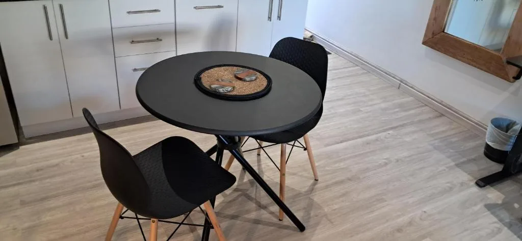 Modern round black dining table with two black chairs and place settings