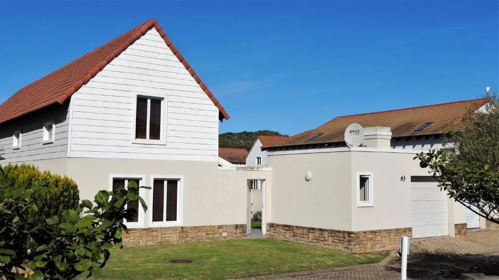 Modern white apartment building with red-tiled roof and stone base