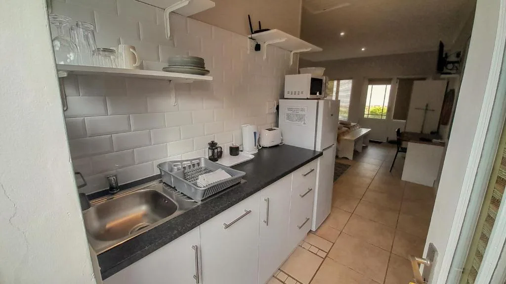 Modern galley kitchen with white cabinetry, black countertop, and stainless steel sink