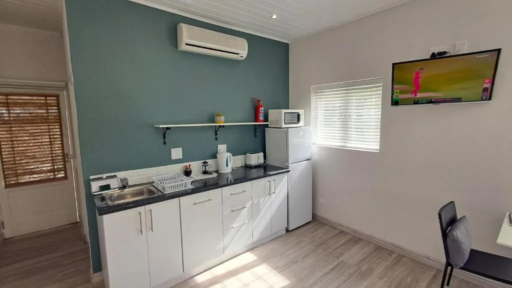 Modern kitchen with white cabinetry, black countertop, and teal accent wall