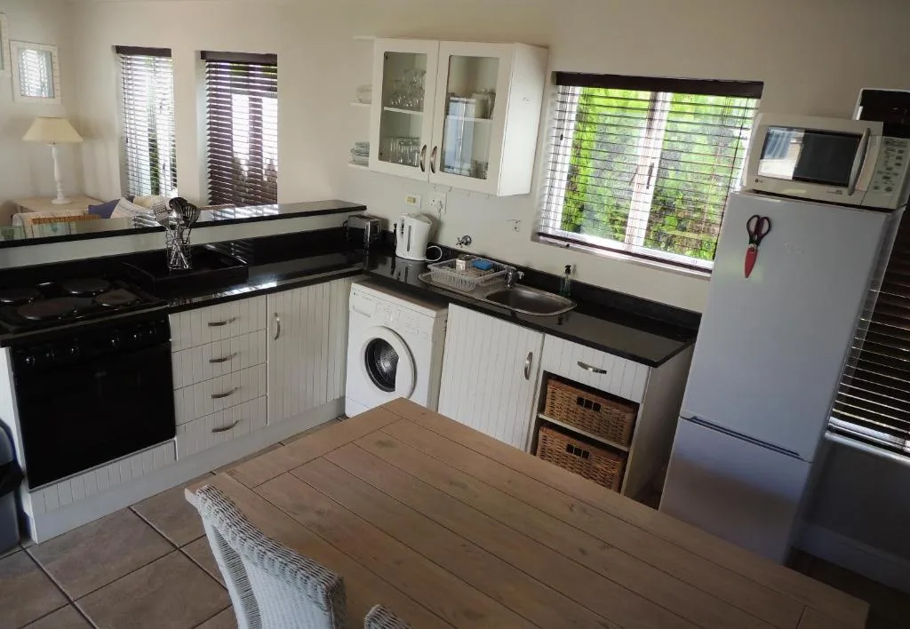 Modern kitchen with black countertops, white cabinetry, stove and refrigerator