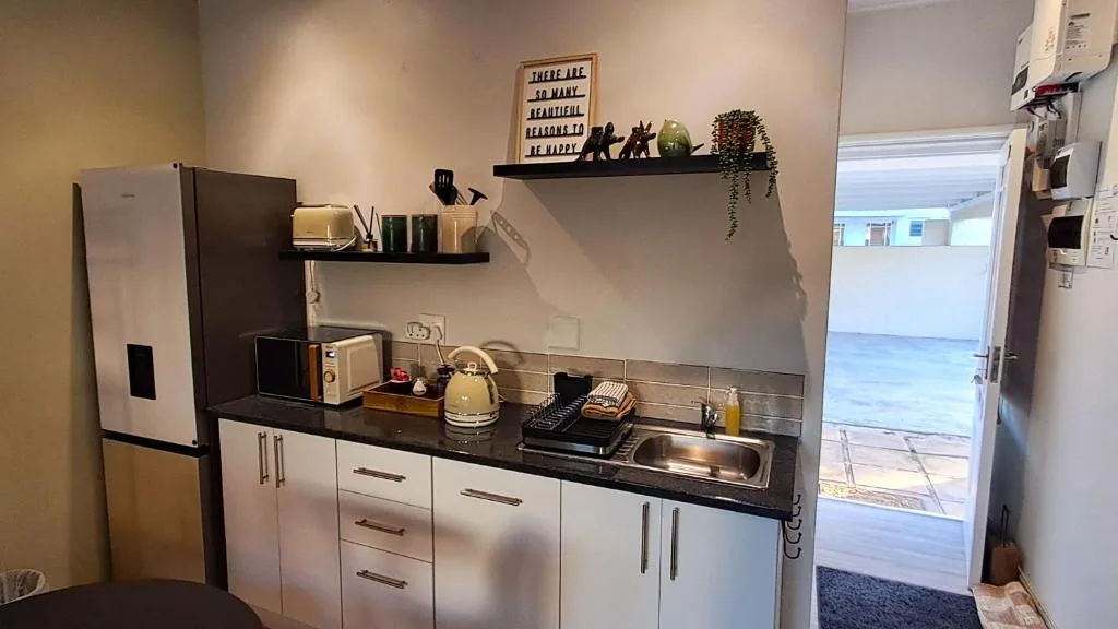 Modern kitchen with white cabinetry, black countertop, and stainless steel sink