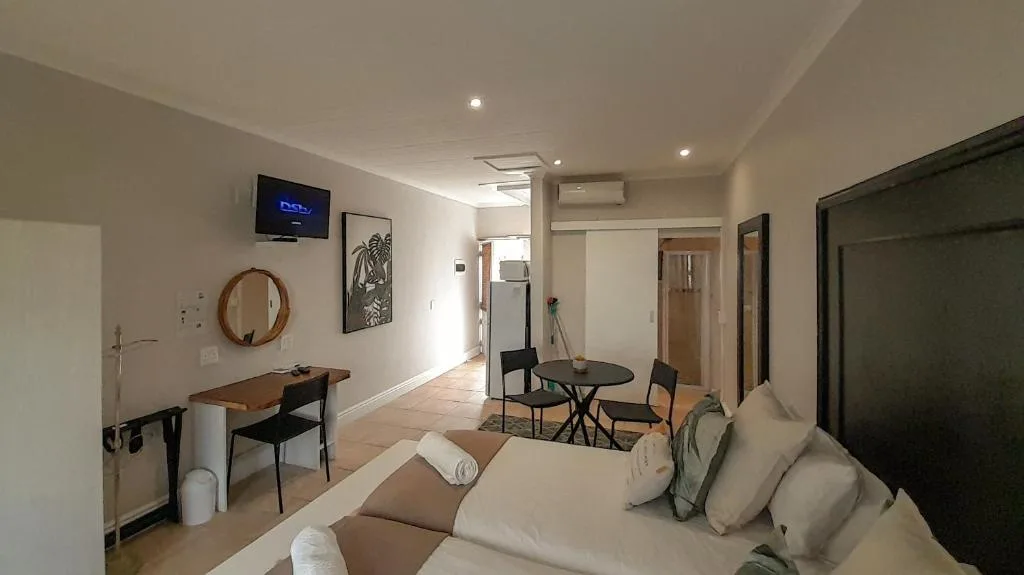 Open-plan lounge with cream sofa, wall-mounted TV, and dining area beyond