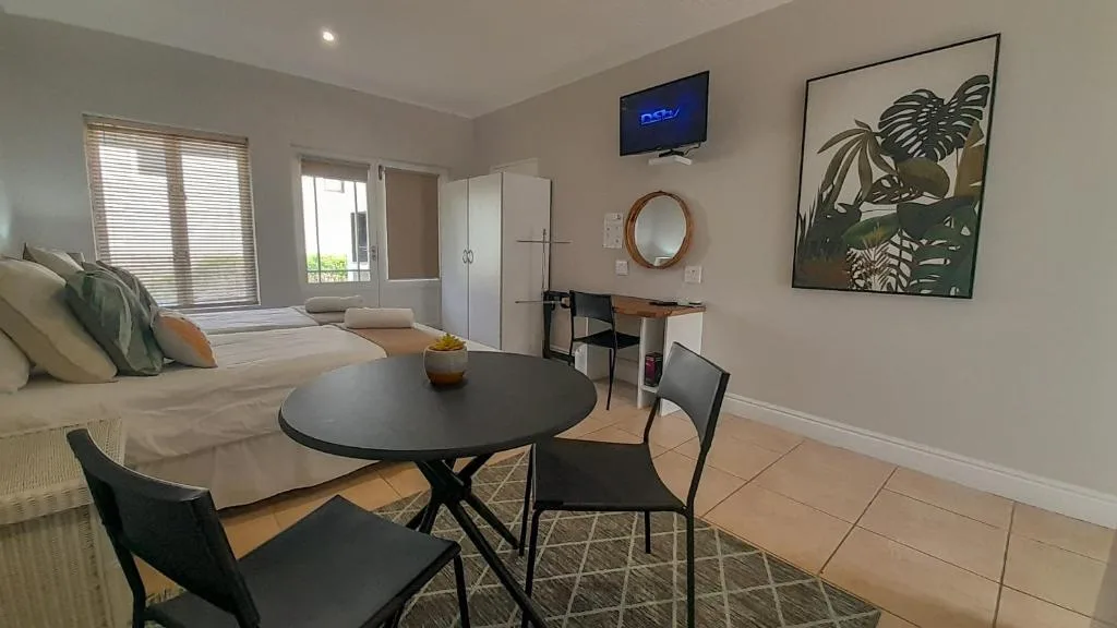 Open-plan lounge and dining area with sofa, round table, and garden artwork