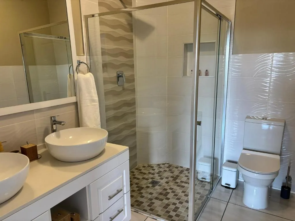 Modern bathroom with round vessel sink, glass shower enclosure, and toilet
