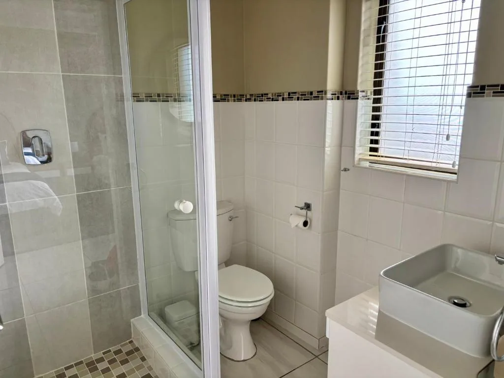 Clean bathroom with glass shower enclosure, toilet, and basin sink