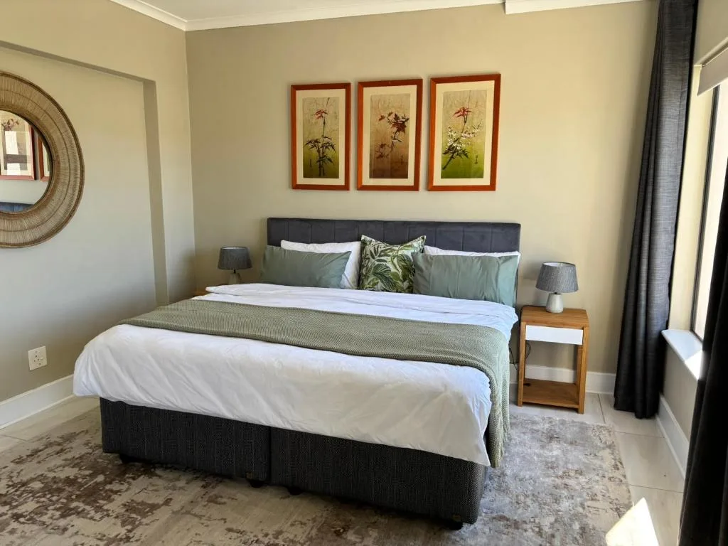 Spacious bedroom with queen bed, botanical artwork, and bedside tables