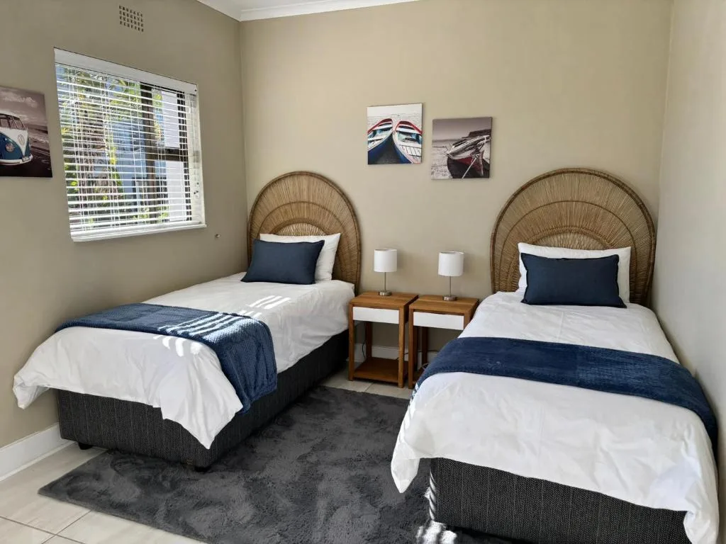 Twin bedroom with woven headboards, white linens, navy accents, and nautical decor