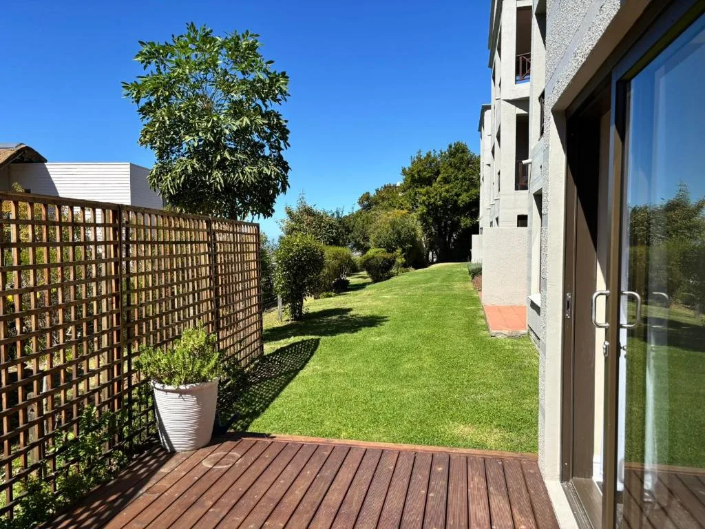 Wooden deck with lattice privacy screen overlooking expansive manicured lawn
