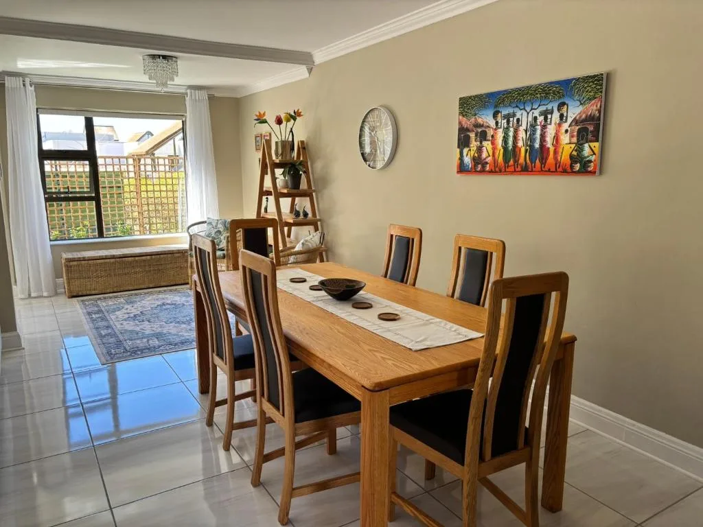 Wooden dining table with six chairs in bright, cream-colored room