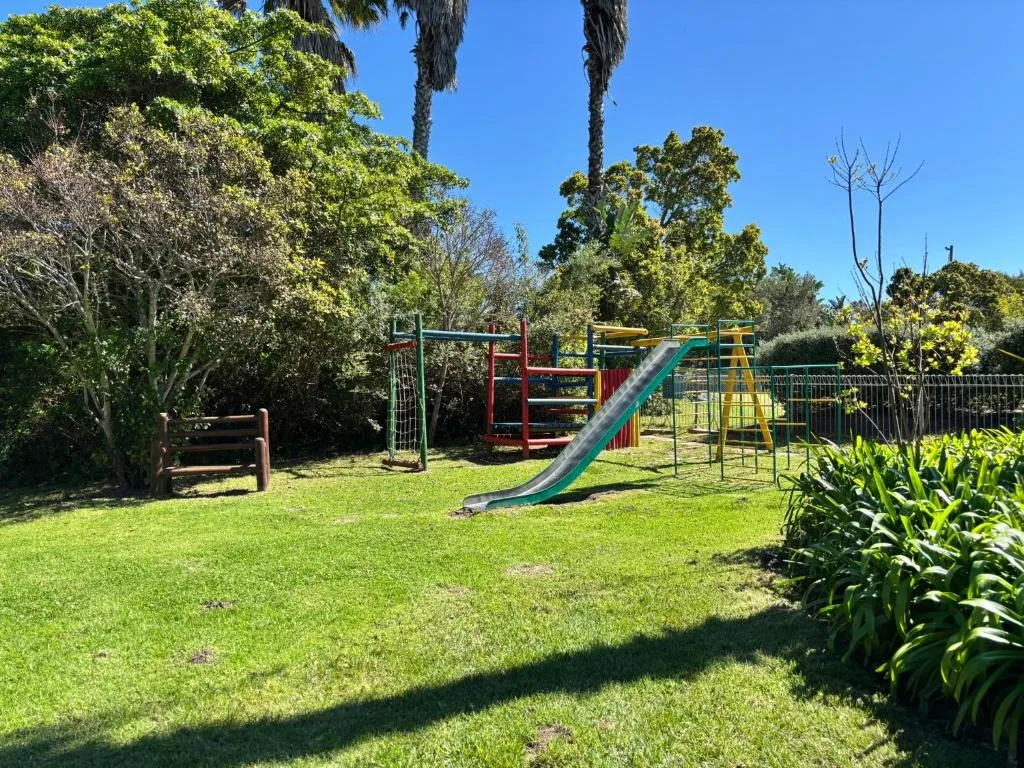 Spacious garden with children's playground equipment and mature trees