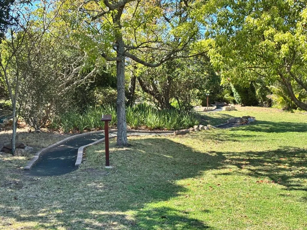 Lush garden grounds with mature trees, manicured lawn, and winding pathways