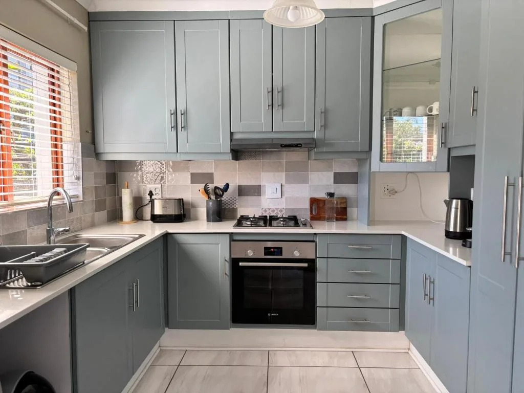 Modern gray kitchen with built-in oven, gas hob, and white countertops
