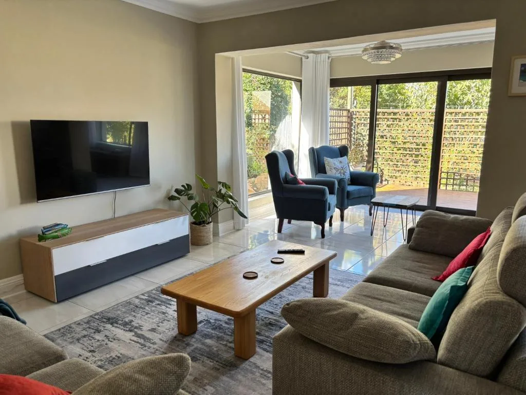 Modern living room with sofas, TV, and access to outdoor deck area