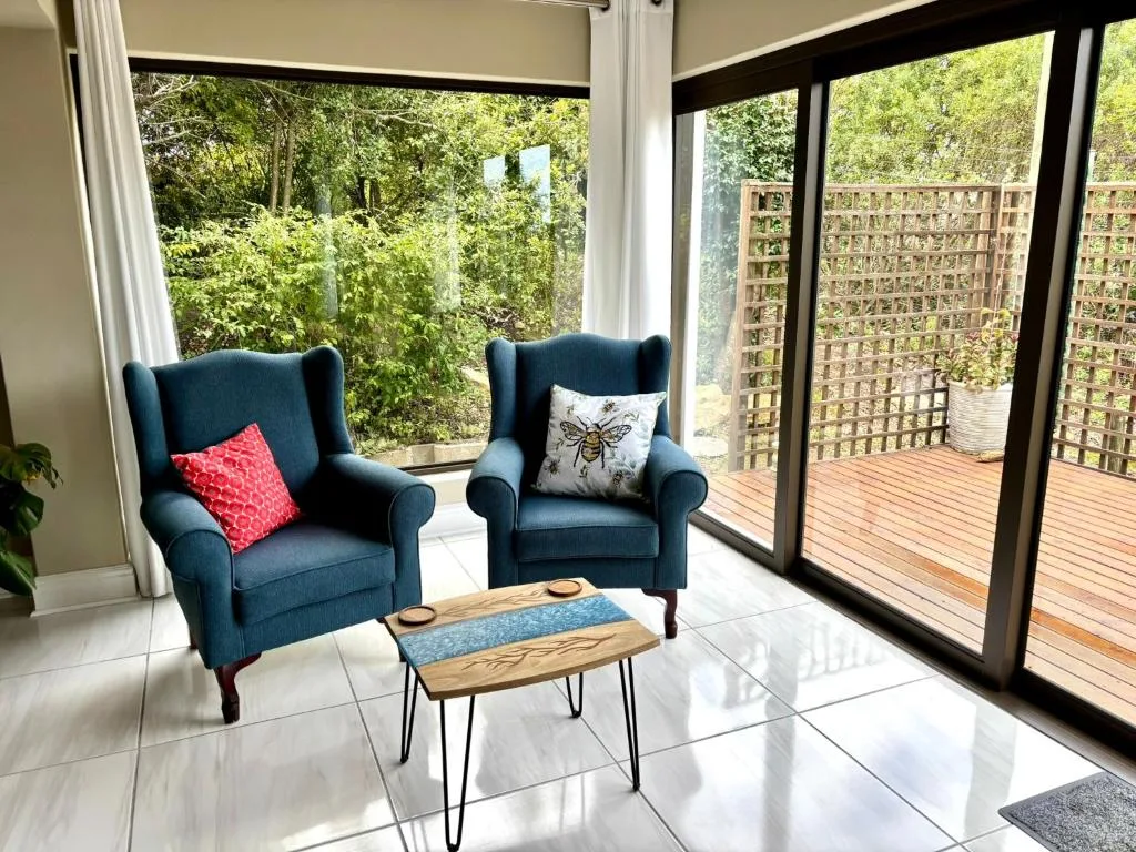 Bright lounge with blue armchairs, wooden coffee table, and garden views