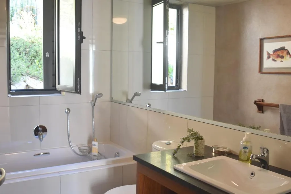 Bright bathroom with bathtub, vanity sink, and large mirror