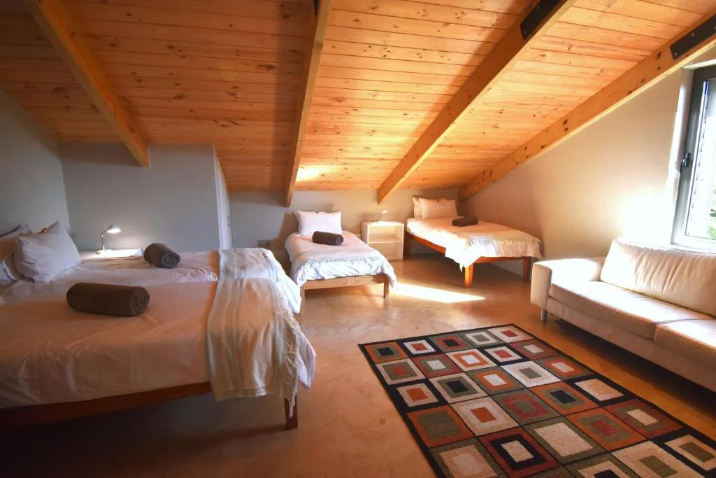Spacious loft bedroom with multiple beds and wooden beamed ceiling
