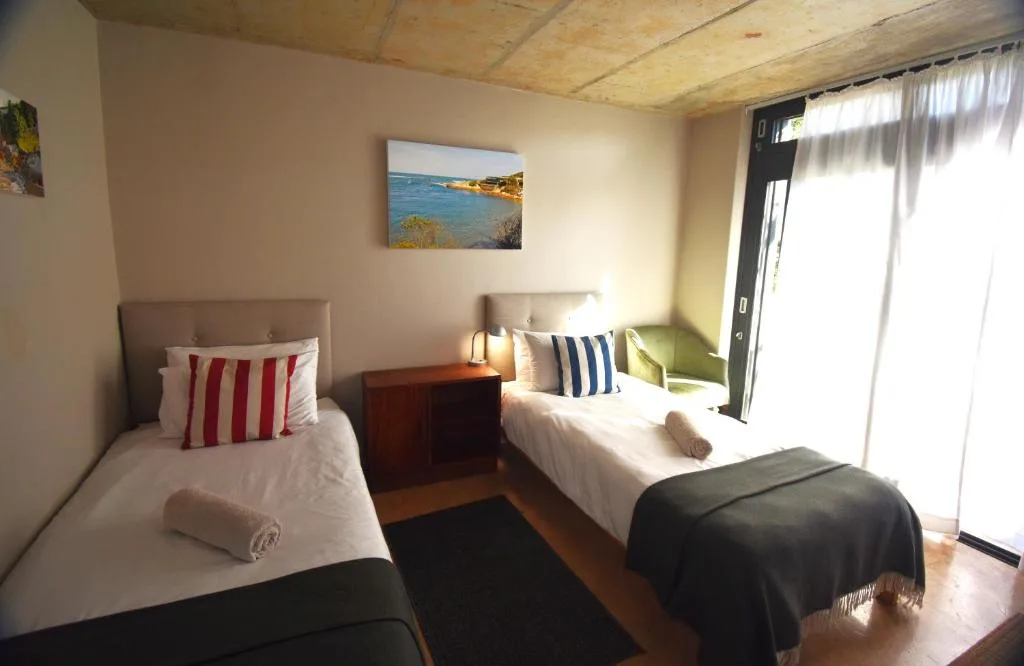 Twin bedroom with white linens, striped pillows, and coastal artwork