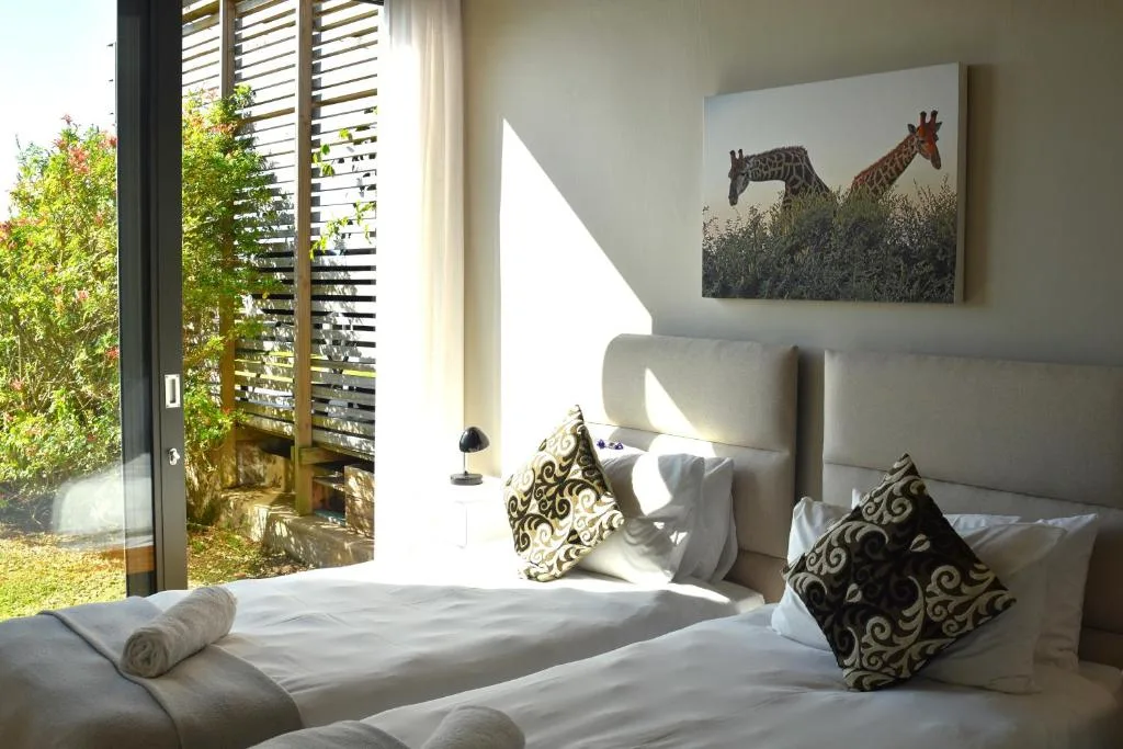 Bright bedroom with double bed, patterned pillows, and garden view through doors