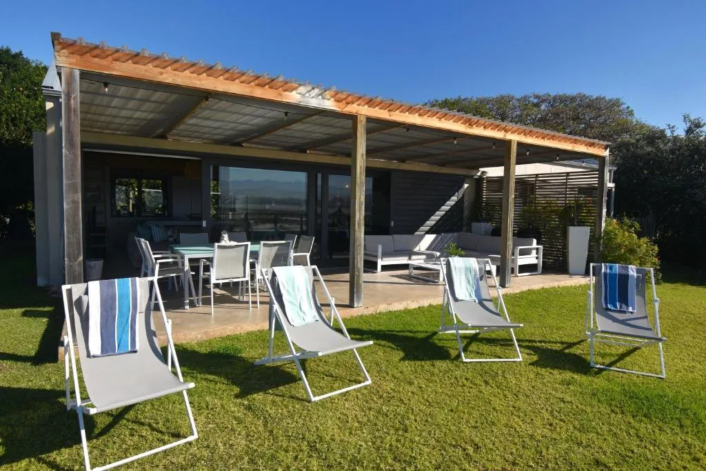 Modern covered deck with dining area, lounge seating, and lawn views
