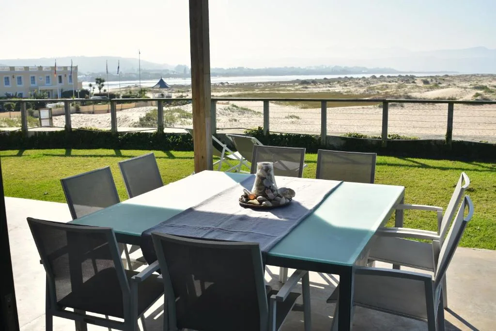 Outdoor dining table with chairs overlooking lagoon and beach landscape
