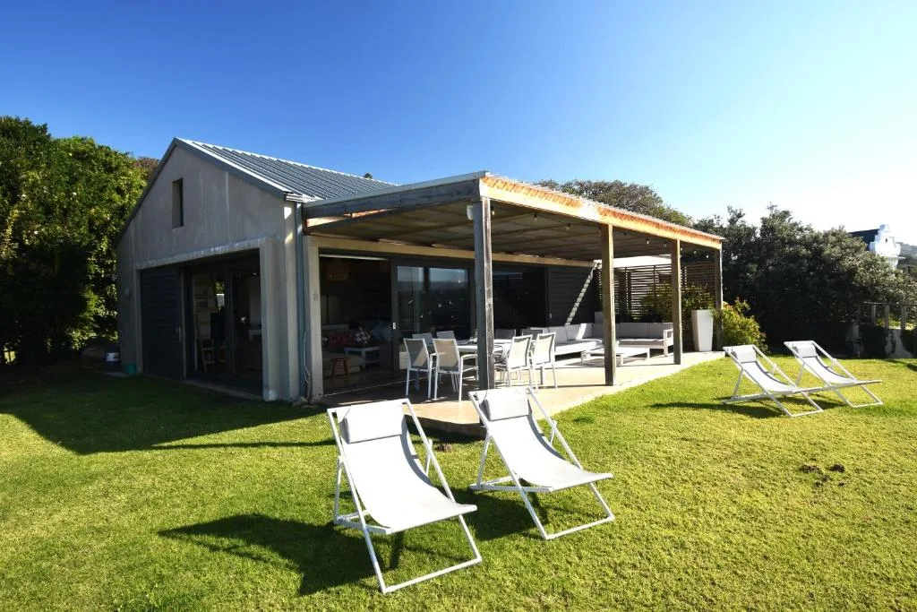Modern gray self-catering cottage with covered deck and manicured garden lawn