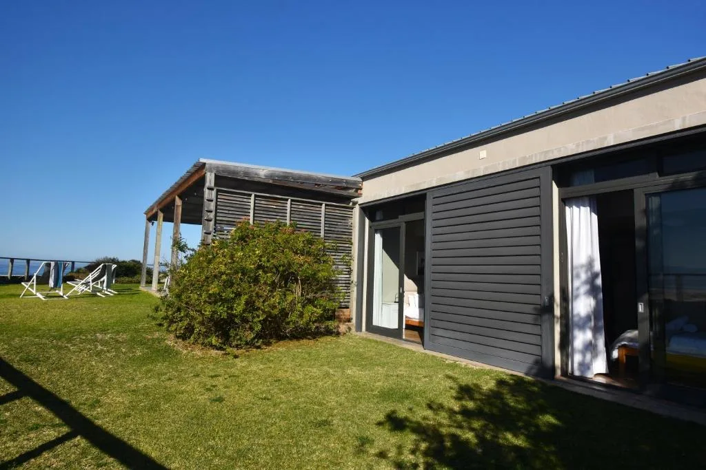 Modern dark timber-clad holiday home with covered deck and manicured lawn