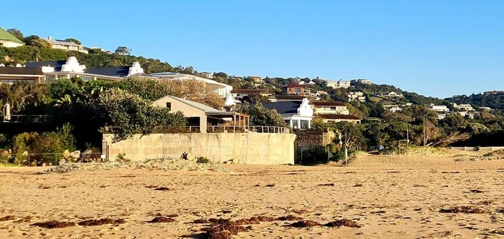 Beachfront property with cream facade and wooden deck overlooking sandy beach