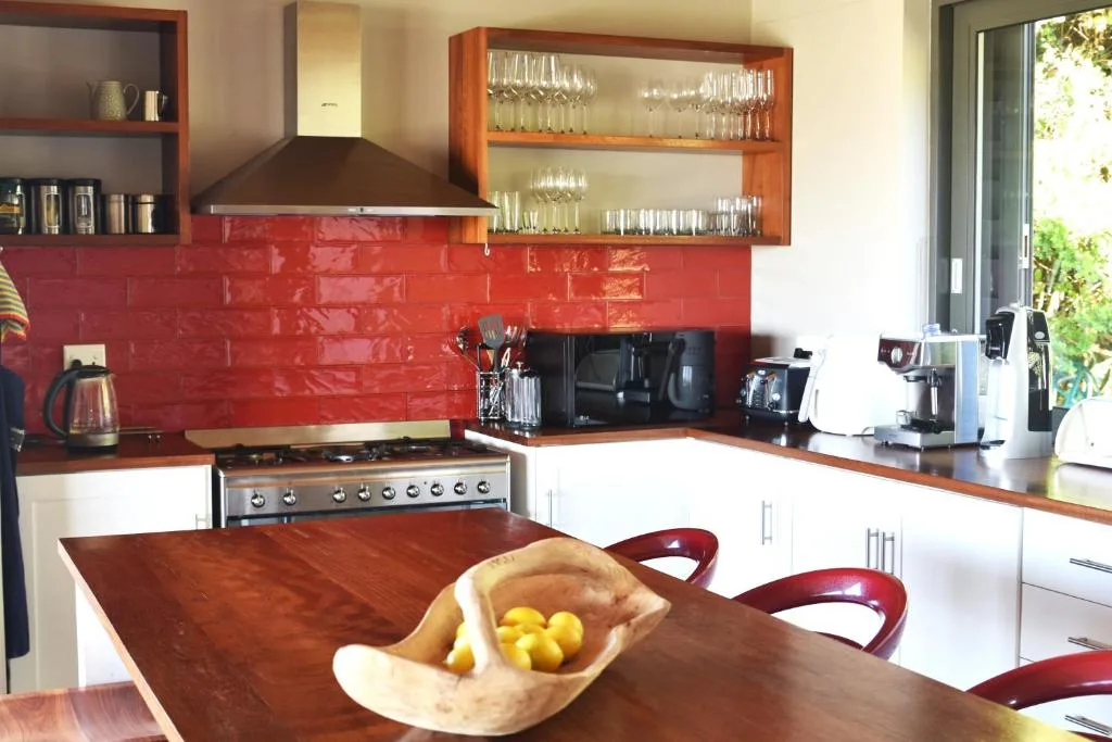 Modern kitchen with red backsplash, wooden counters, and stainless steel stove