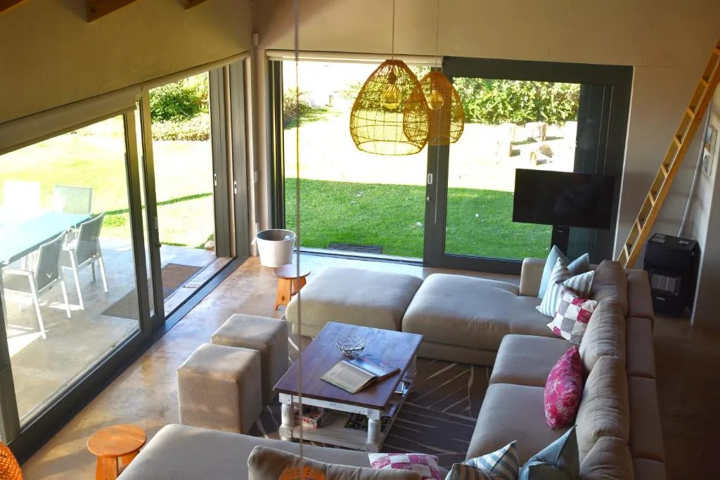 Modern living room with comfortable seating, hanging chair, and garden views