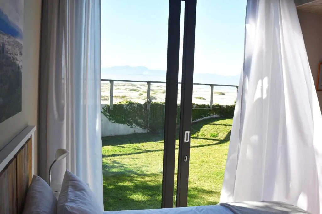 Coastal landscape visible through open glass doors from bedroom