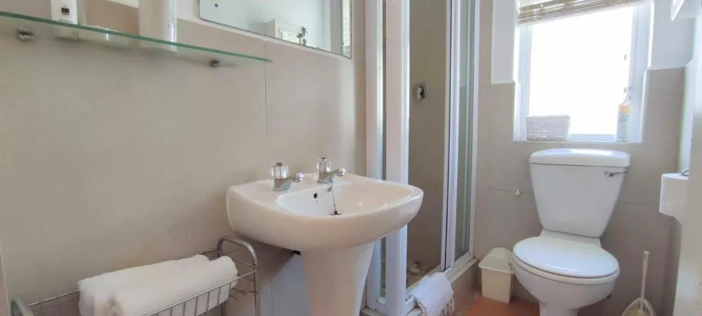 Clean modern bathroom with pedestal sink, toilet, and shower enclosure