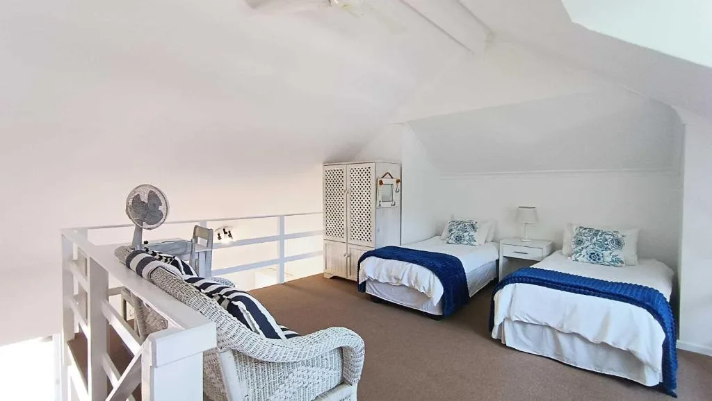 Bright bedroom with two twin beds dressed in white linens and blue throws