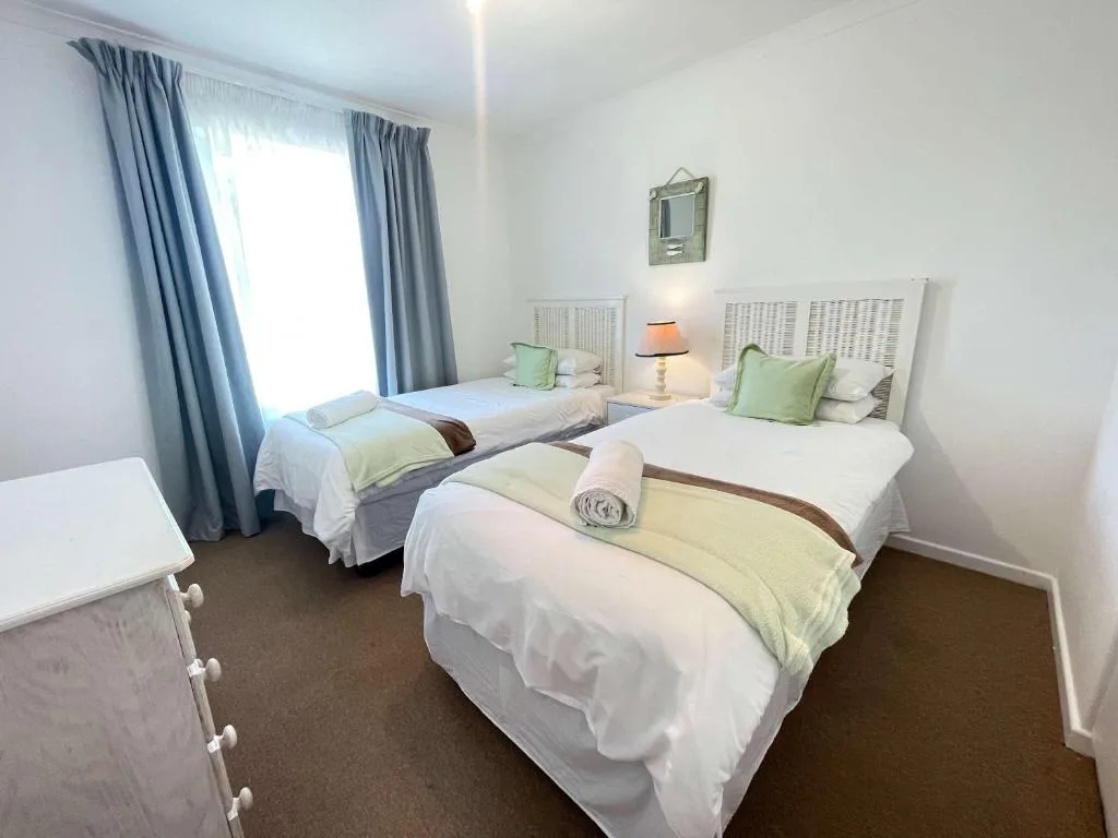 Bright bedroom with three single beds and blue curtains