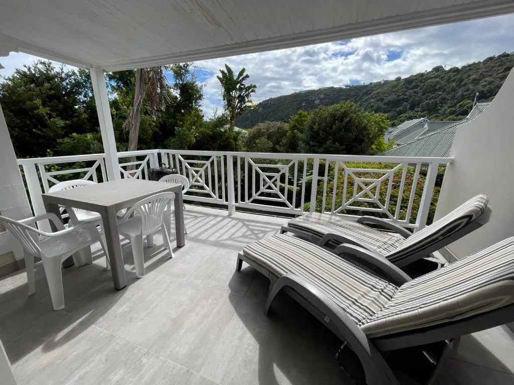 Shaded deck with loungers and dining furniture overlooking forested valley