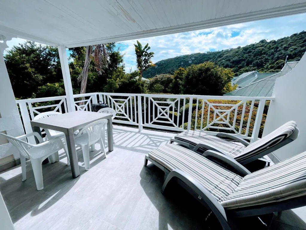 Spacious covered deck with loungers and dining table overlooking forested valley