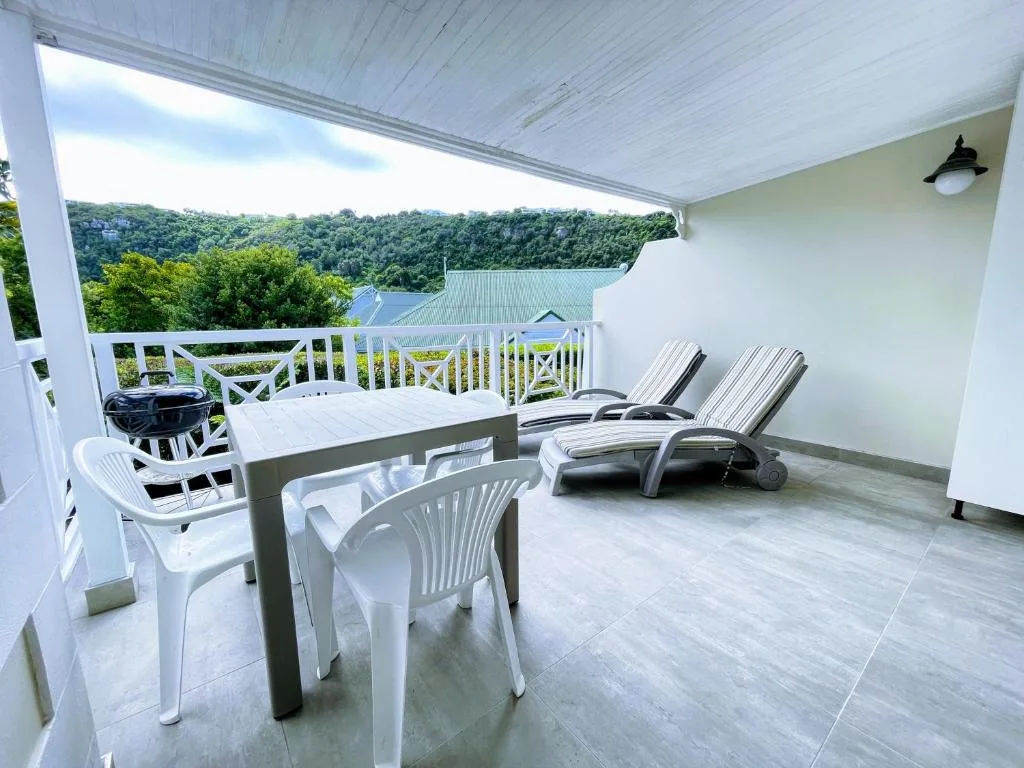 Covered deck with dining table, loungers, and lagoon view