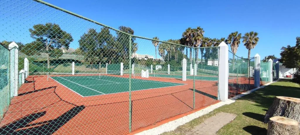 Tennis courts with red clay surface and white fencing on property grounds