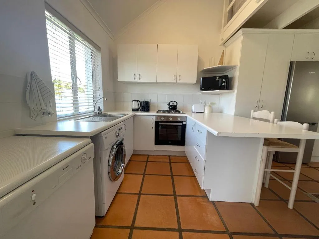 Bright white kitchen with oven, washing machine, and island counter
