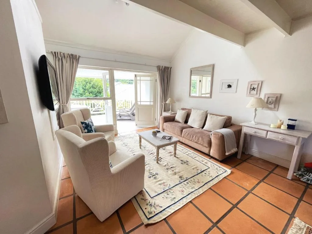 Bright lounge with cream armchairs, mauve sofa, and terracotta tile flooring