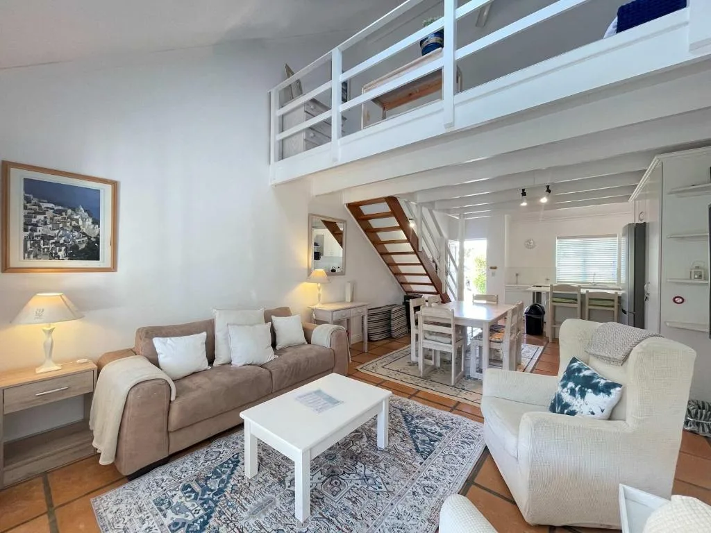 Open-plan living area with comfortable seating and wooden stairs to loft