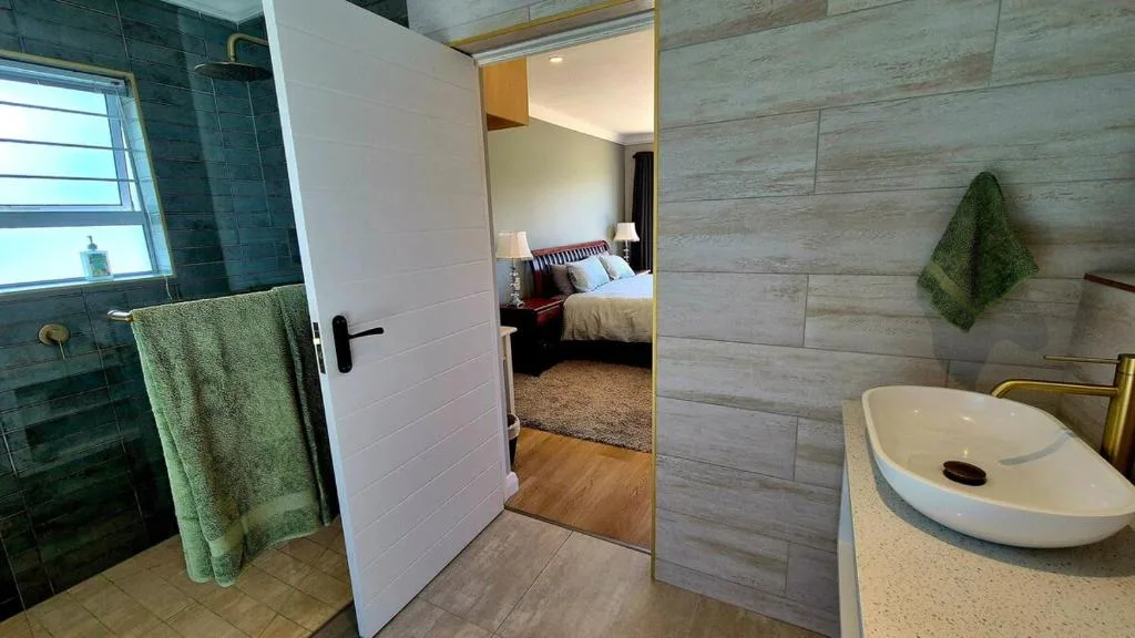 Modern bathroom with vessel sink, rainfall shower, and green accents