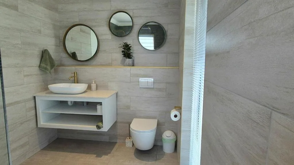 Modern bathroom with round mirrors, vessel sink, and toilet fixture