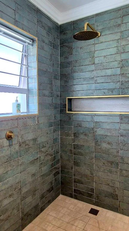 Modern walk-in shower with slate-grey tiles and brass fixtures