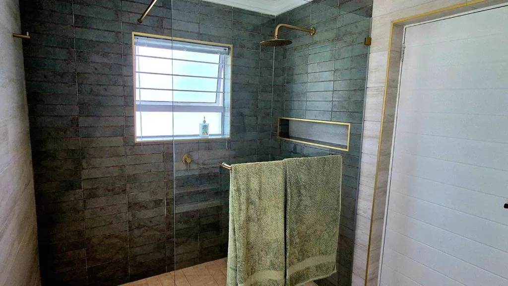 Modern bathroom with dark tile shower enclosure and brass fixtures