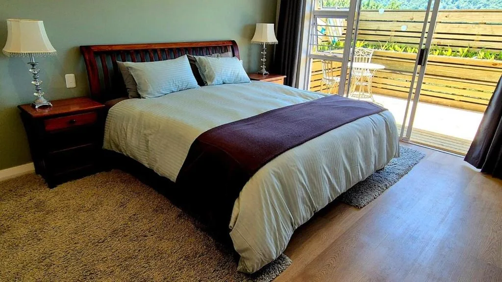 Spacious bedroom with queen bed, wooden furniture, and glass doors opening to deck