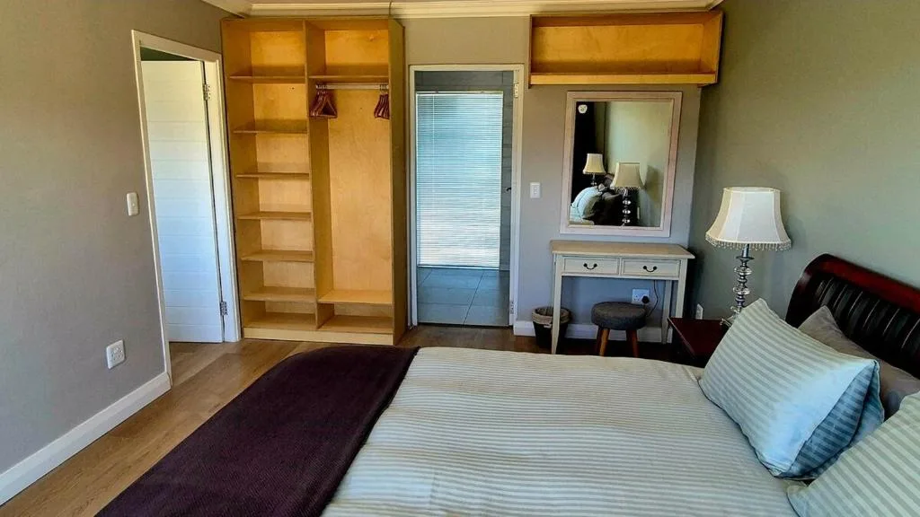 Spacious bedroom with double bed, wooden wardrobe, and vanity mirror