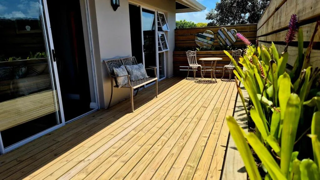 Wooden deck with seating, potted plants, and garden furniture overlooking trees